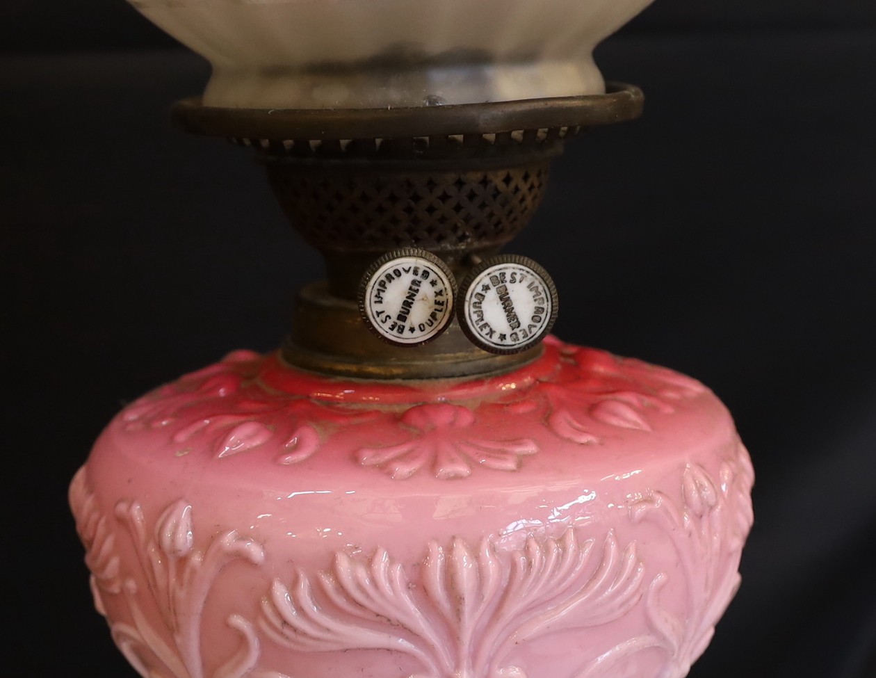 A late Victorian brass and opaque pink glass oil lamp, with Burnes duplex mechanism, pink tinted etched glass globe and flue, height overall 71cm